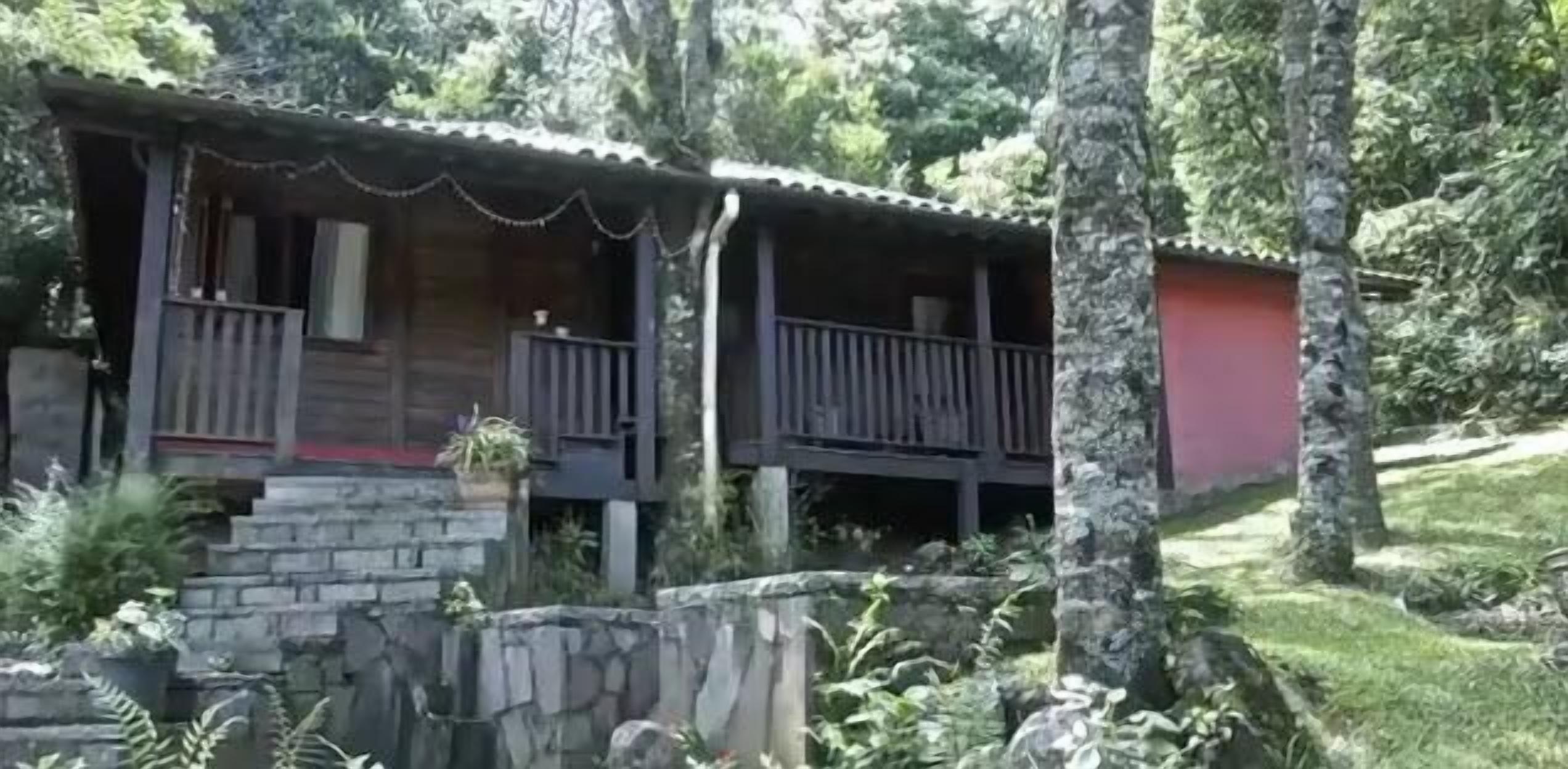 A rustic cabin with a stone foundation, wooden exterior, and a balcony.