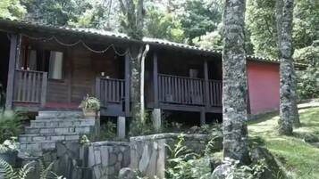 A rustic cabin with a stone foundation, wooden exterior, and a balcony.