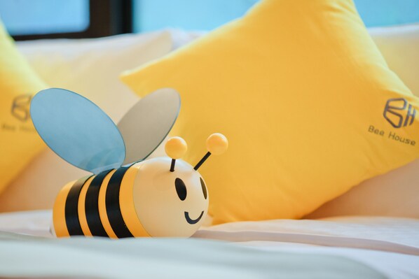 A bed with yellow pillows and a toy bee.