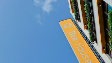 Um edifício com uma placa que diz "Bee House" e um céu azul claro ao fundo.