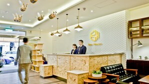 A reception area with a modern design, featuring a reception desk, a black leather sofa, and a wall with a honeycomb pattern. - Bee House by Cosmos Creation-Taipei Main Station (Taipei)