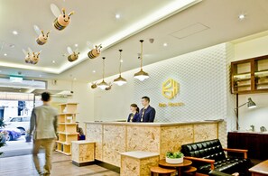 A reception area with a modern design, featuring a reception desk, a black leather sofa, and a wall with a honeycomb pattern.