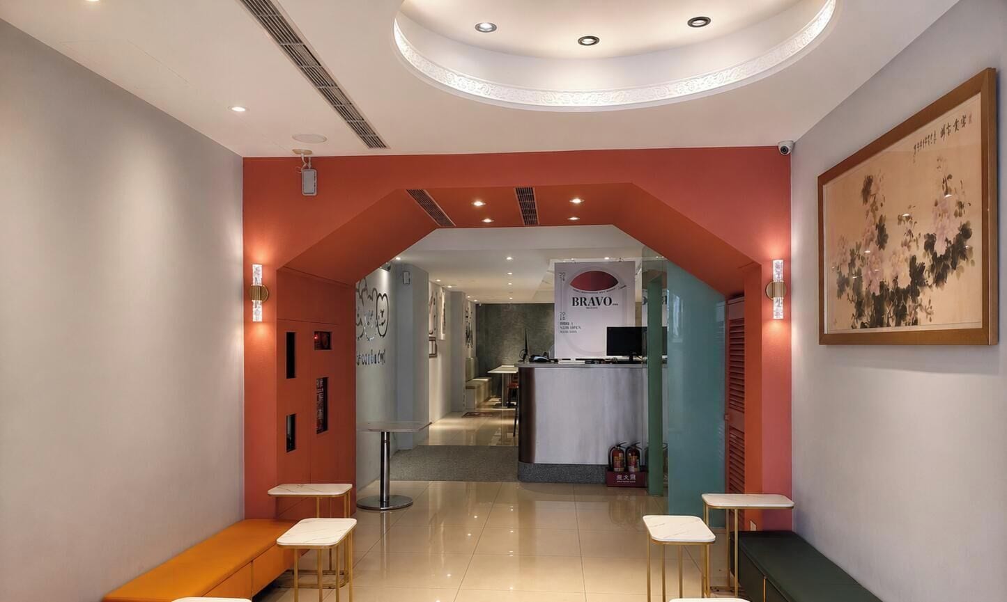 A hotel lobby with a reception desk, seating areas, and a framed artwork on the wall.