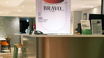 A hotel reception desk with a large sign announcing a new opening.