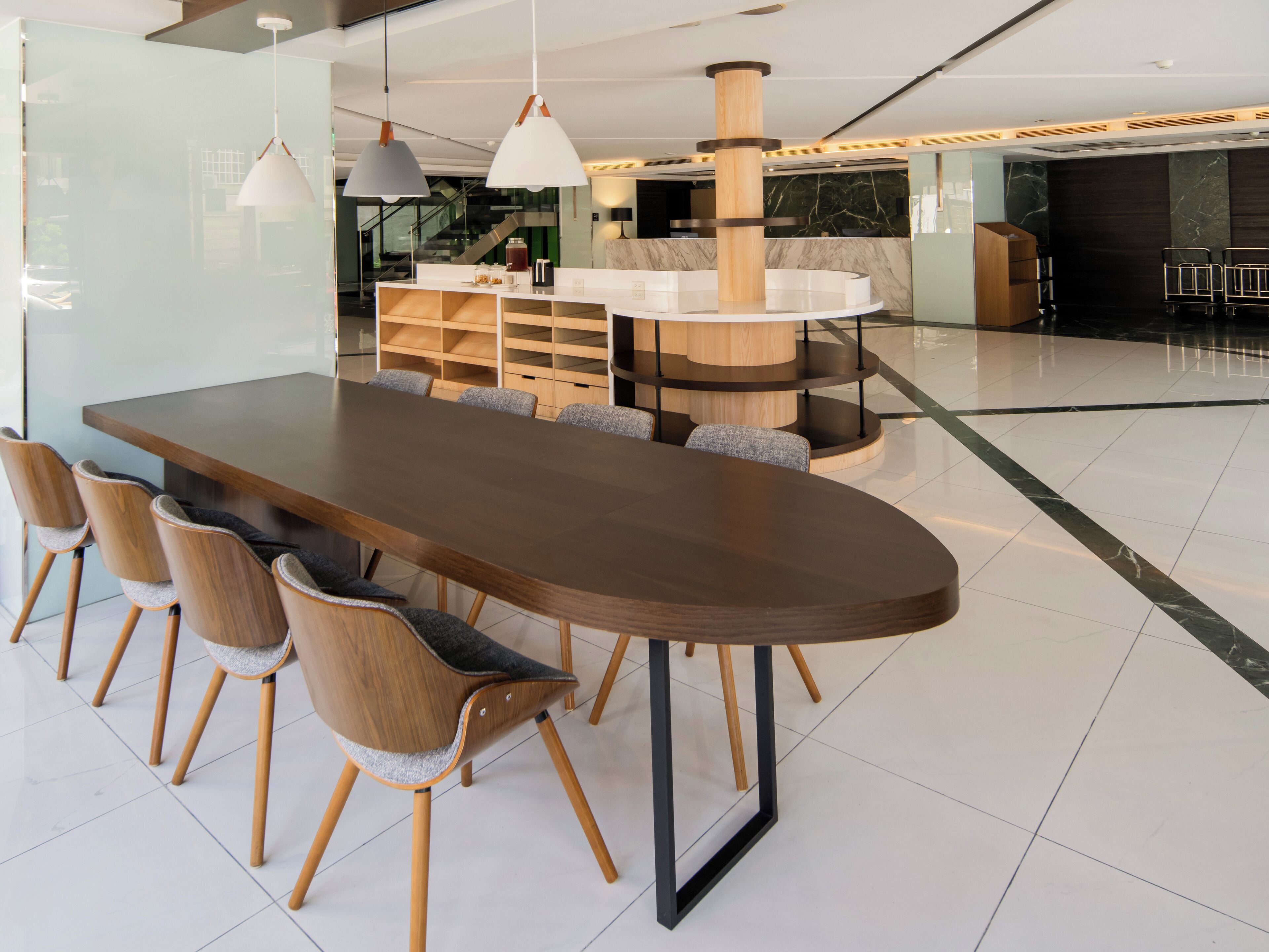 A modern dining area with a long wooden table, six chairs, and pendant lighting.