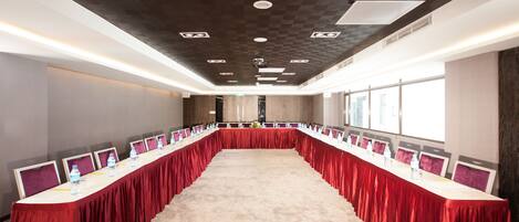 A conference room with a long table, red tablecloth, and multiple monitors.