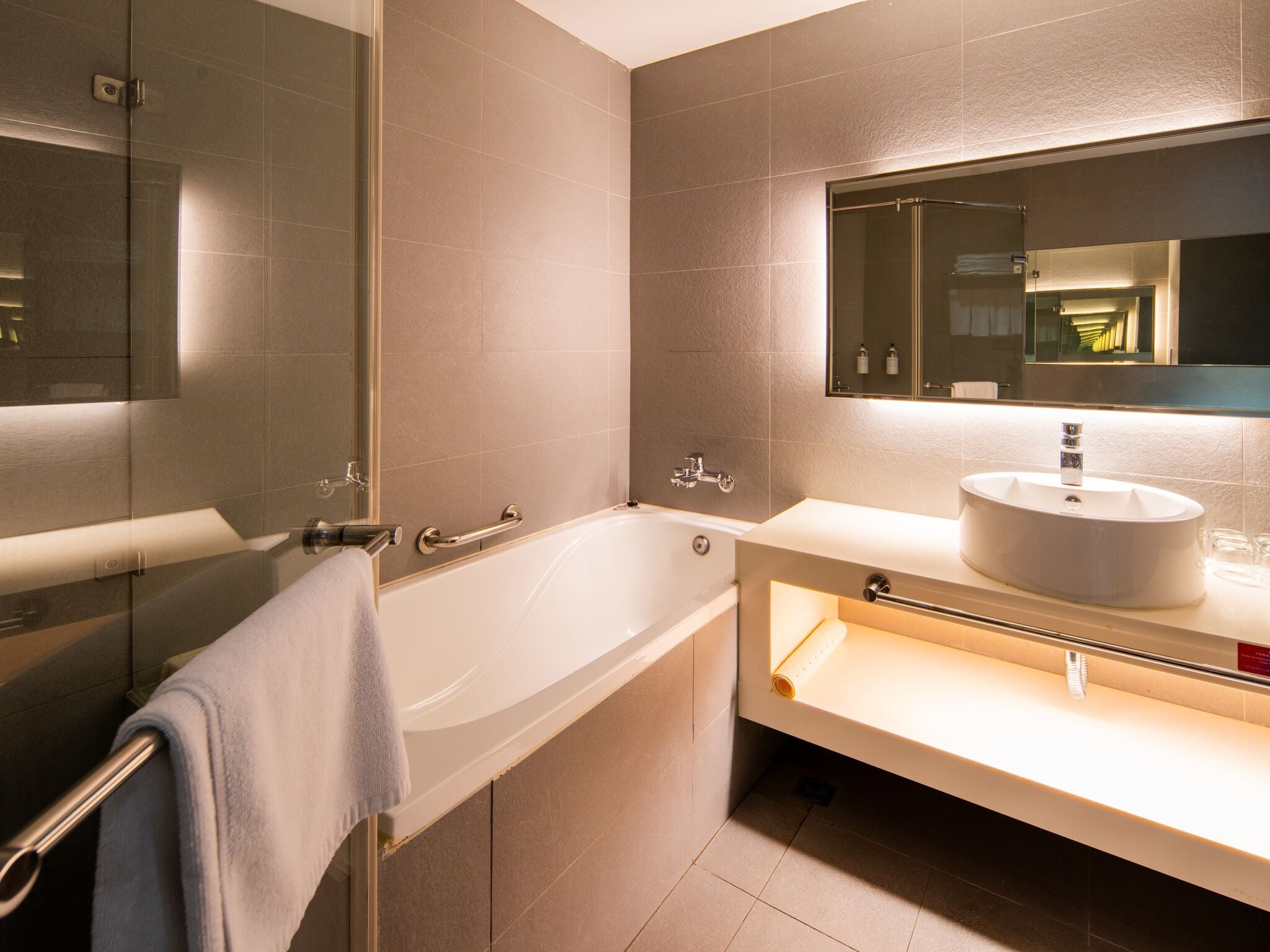 A modern bathroom with a bathtub, a sink, and a mirror.
