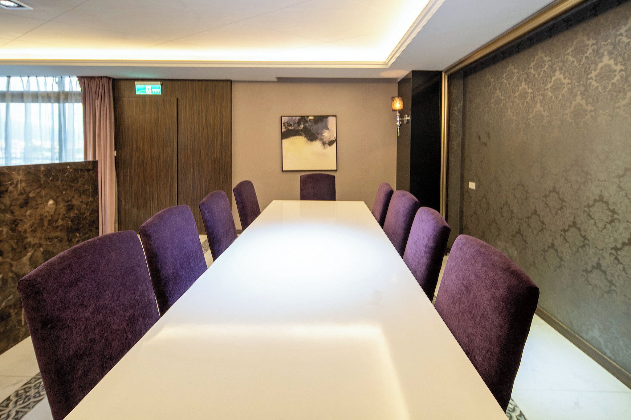 Ein Konferenzraum mit einem langen Tisch und sechs violetten Stühlen.