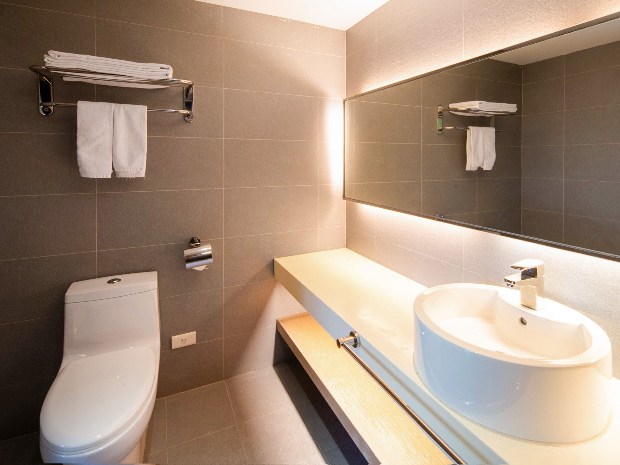 A modern bathroom with a toilet, a sink, and a large mirror.