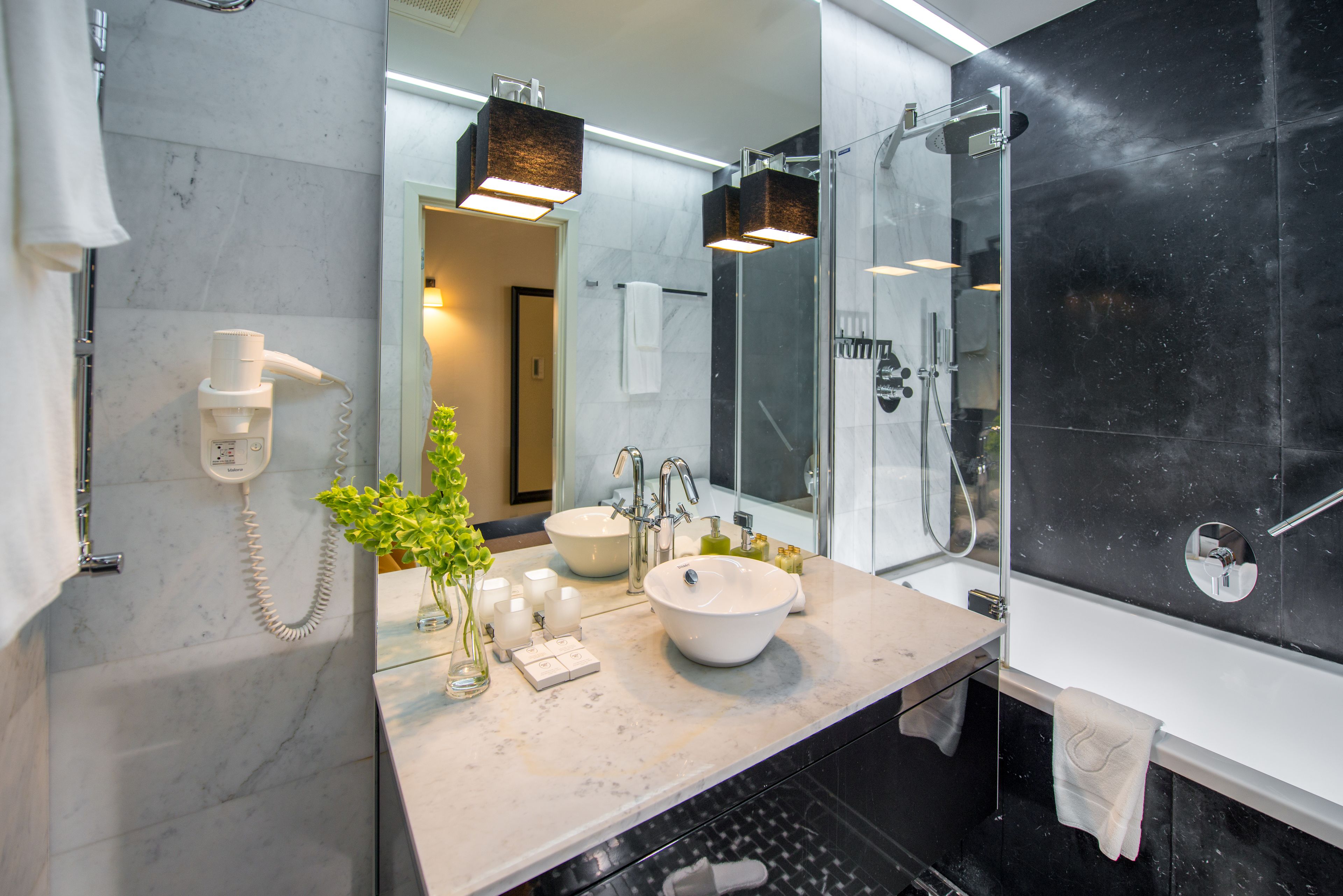A modern bathroom with a large mirror, a sink, a shower, and a telephone.