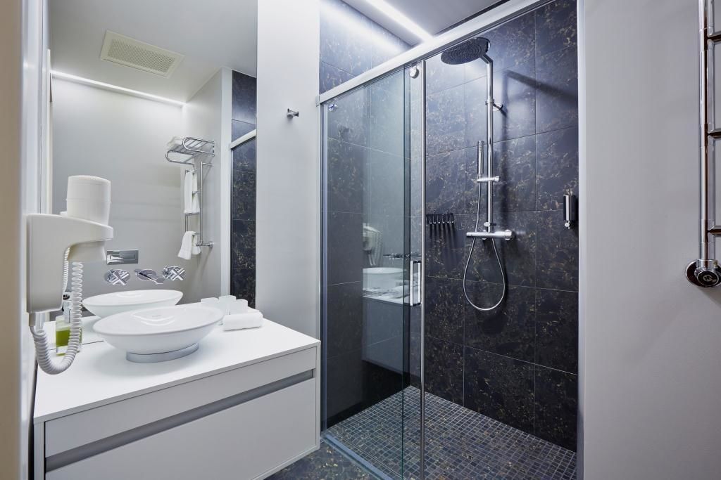 A modern bathroom with a glass-enclosed shower, a white vanity with two sinks, and a towel rack.