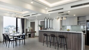 A modern kitchen with a central island, bar stools, and a dining area with chairs. - Flower Garden Hotel (Hanoi)