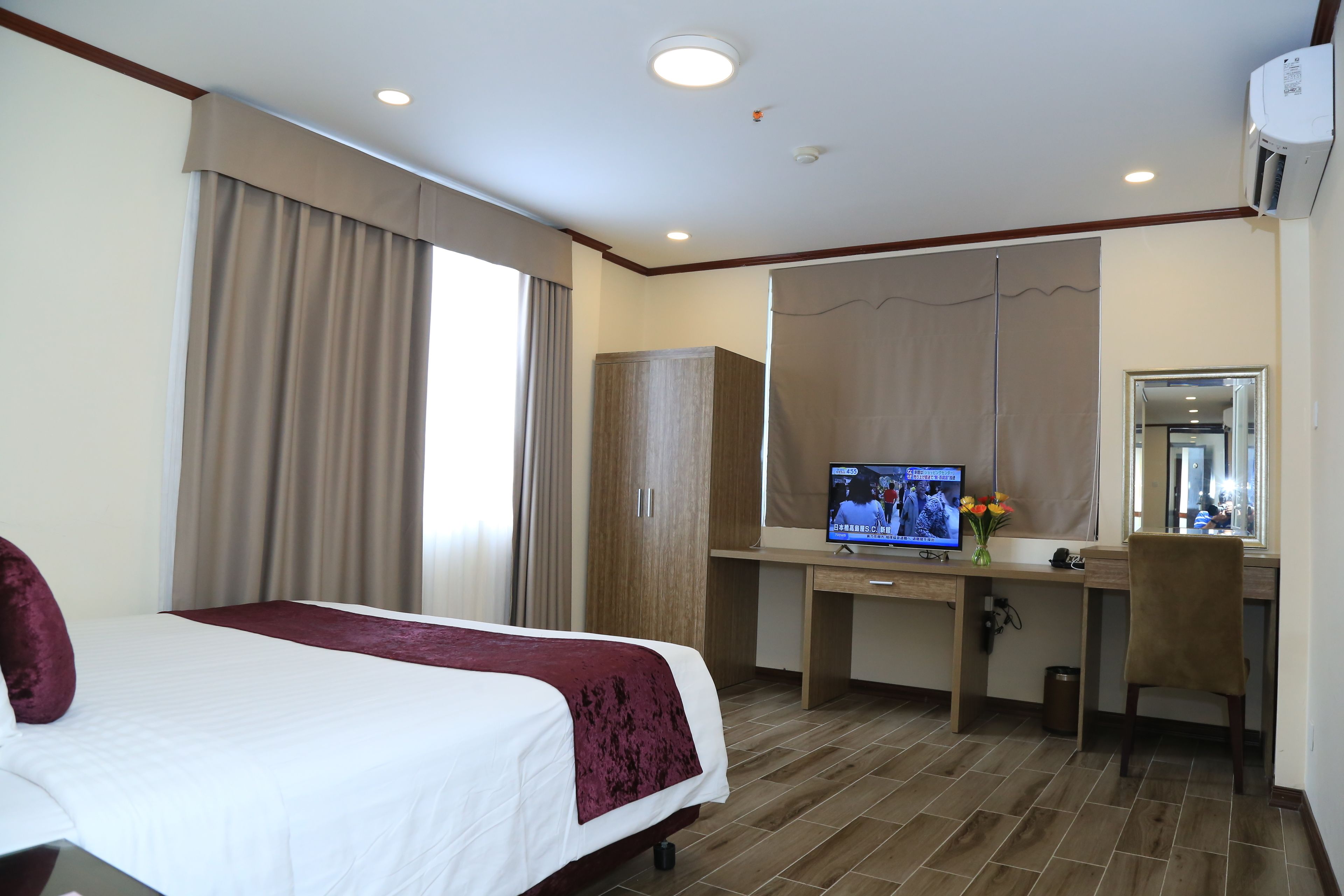 A hotel room with a bed, a desk, a television, and a wardrobe.