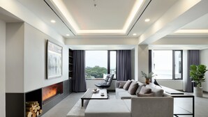 A modern living room with a fireplace, a sofa, a coffee table, and a view of the city. - Flower Garden Hotel (Hanoi)