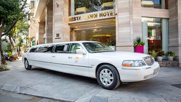 A white limousine parked in front of the NESTA HANOI HOTEL.