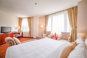 A hotel room with a large bed, a desk with a television, two armchairs, and a small table with a bottle and glasses. -  Nesta Hotel Ha Noi (Hanoi)