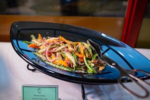 A blue glass plate with a shredded chicken salad, accompanied by a pair of scissors. -  Nesta Hotel Ha Noi (Hanoi)