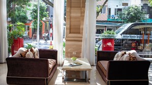 A modern hotel lobby with two sofas, a coffee table, and a view of the street outside. -  Nesta Hotel Ha Noi (Hanoi)