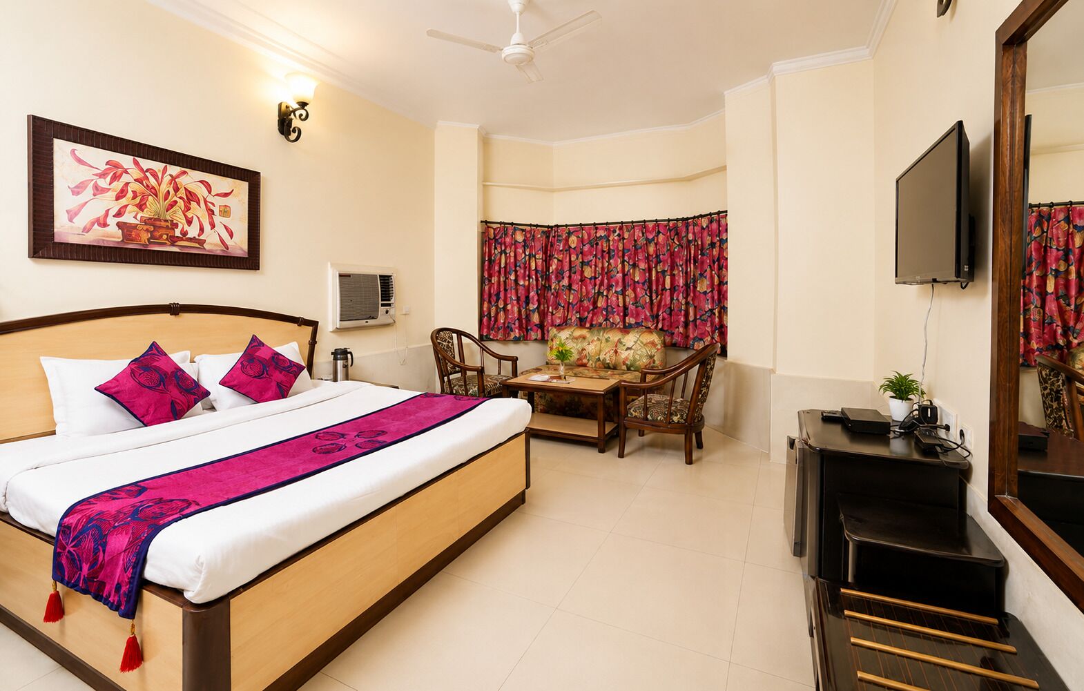 A hotel room with a bed, a desk, a chair, a television, and a window with curtains.