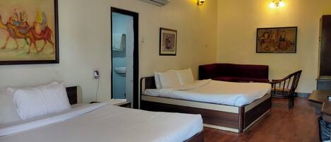 A hotel room with two beds, a bathroom, and artwork on the walls.