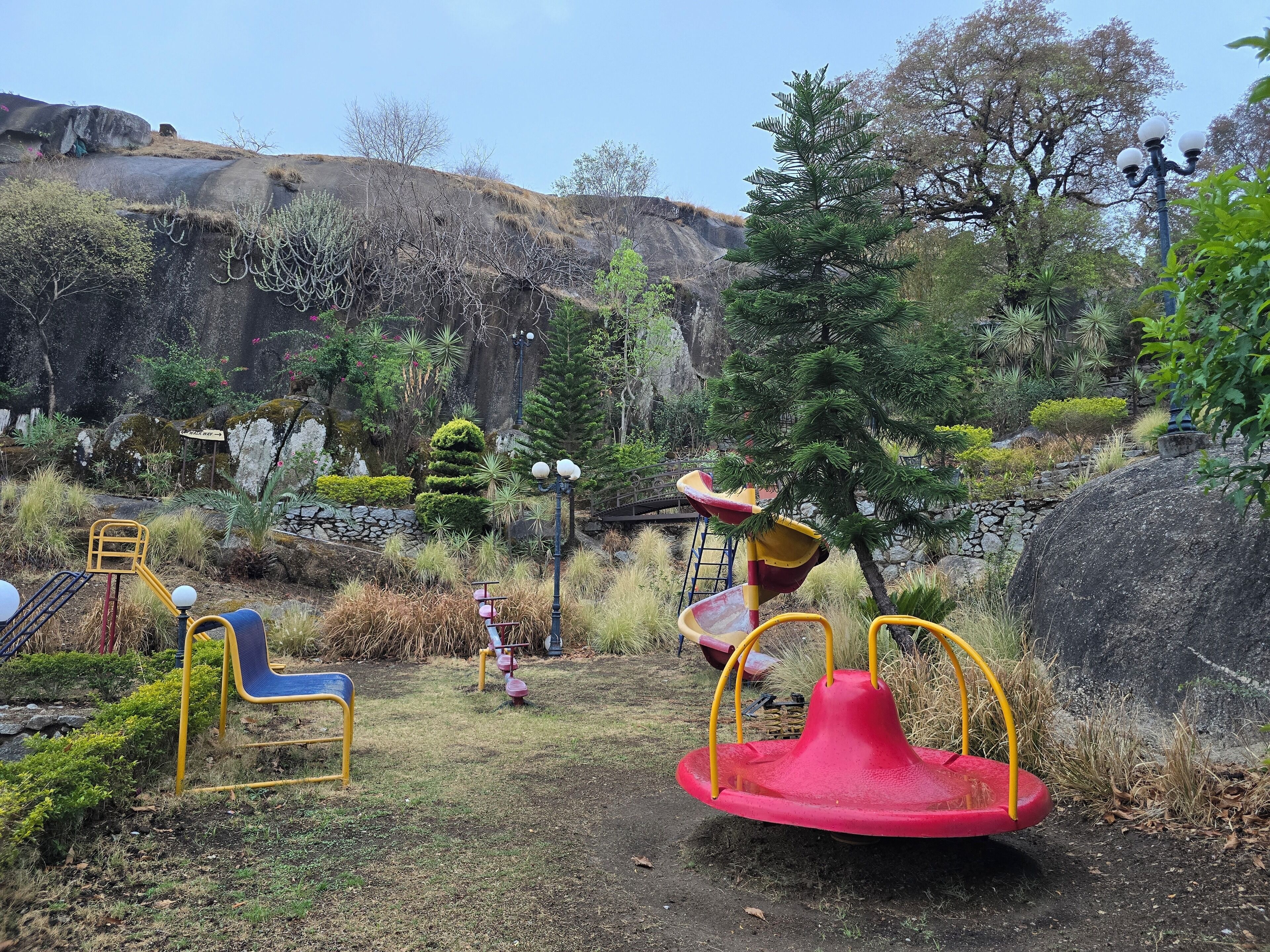 A playground with a red swing set, yellow and blue play equipment, and a slide.