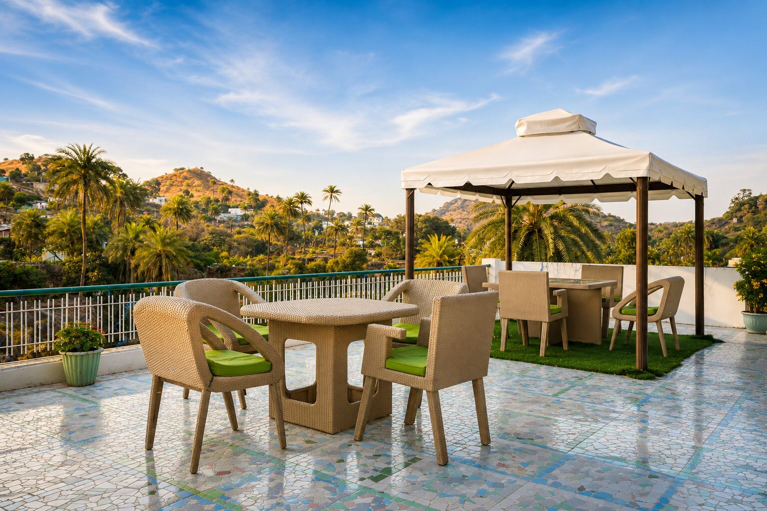 An outdoor patio with wicker furniture, a white canopy, and a view of palm trees and hills.