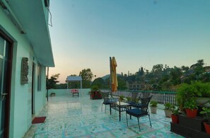 Una terraza en la azotea con suelo de baldosas, mobiliario exterior y plantas en macetas.