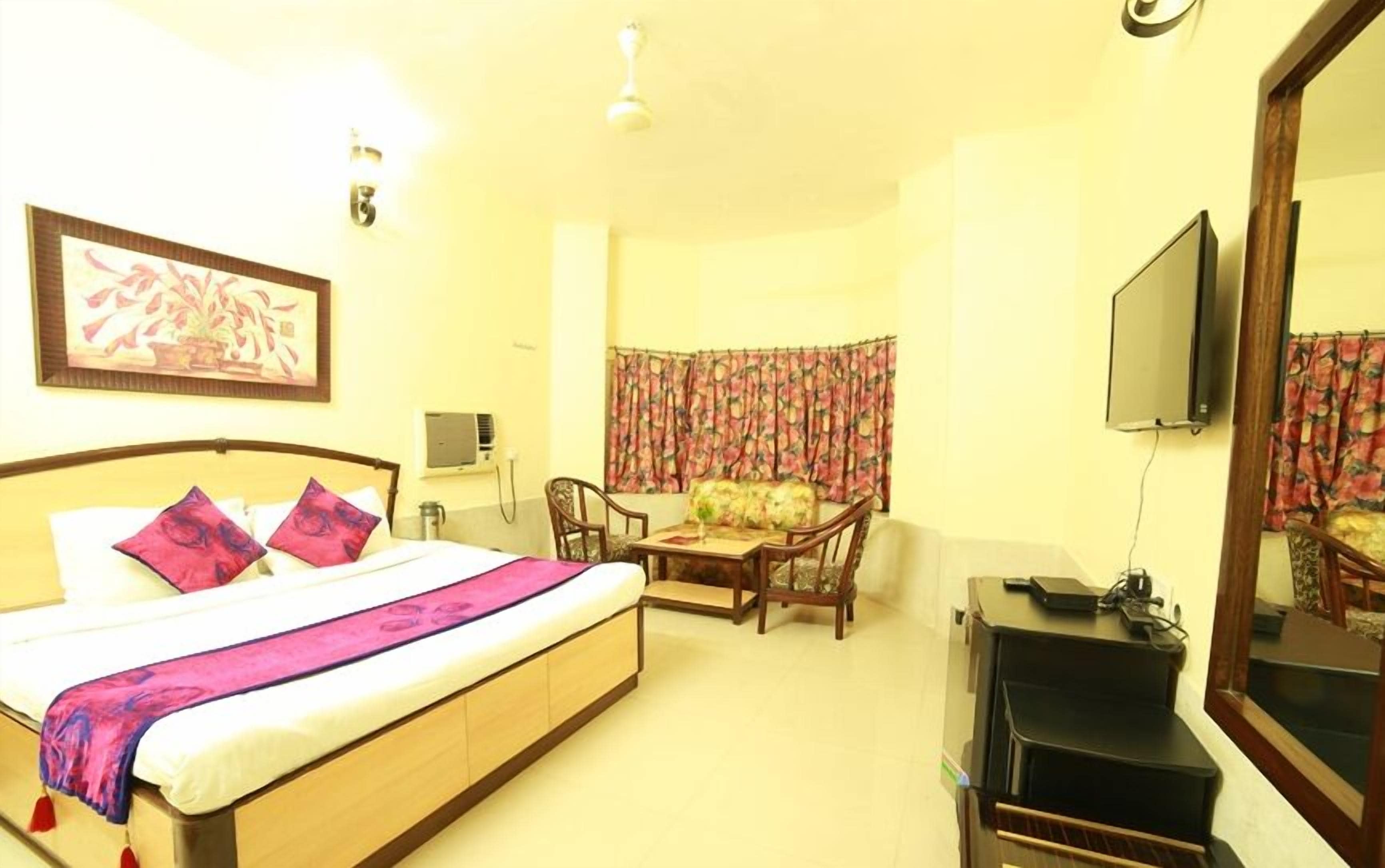 A hotel room with a bed, a desk, a chair, a television, and a mirror.