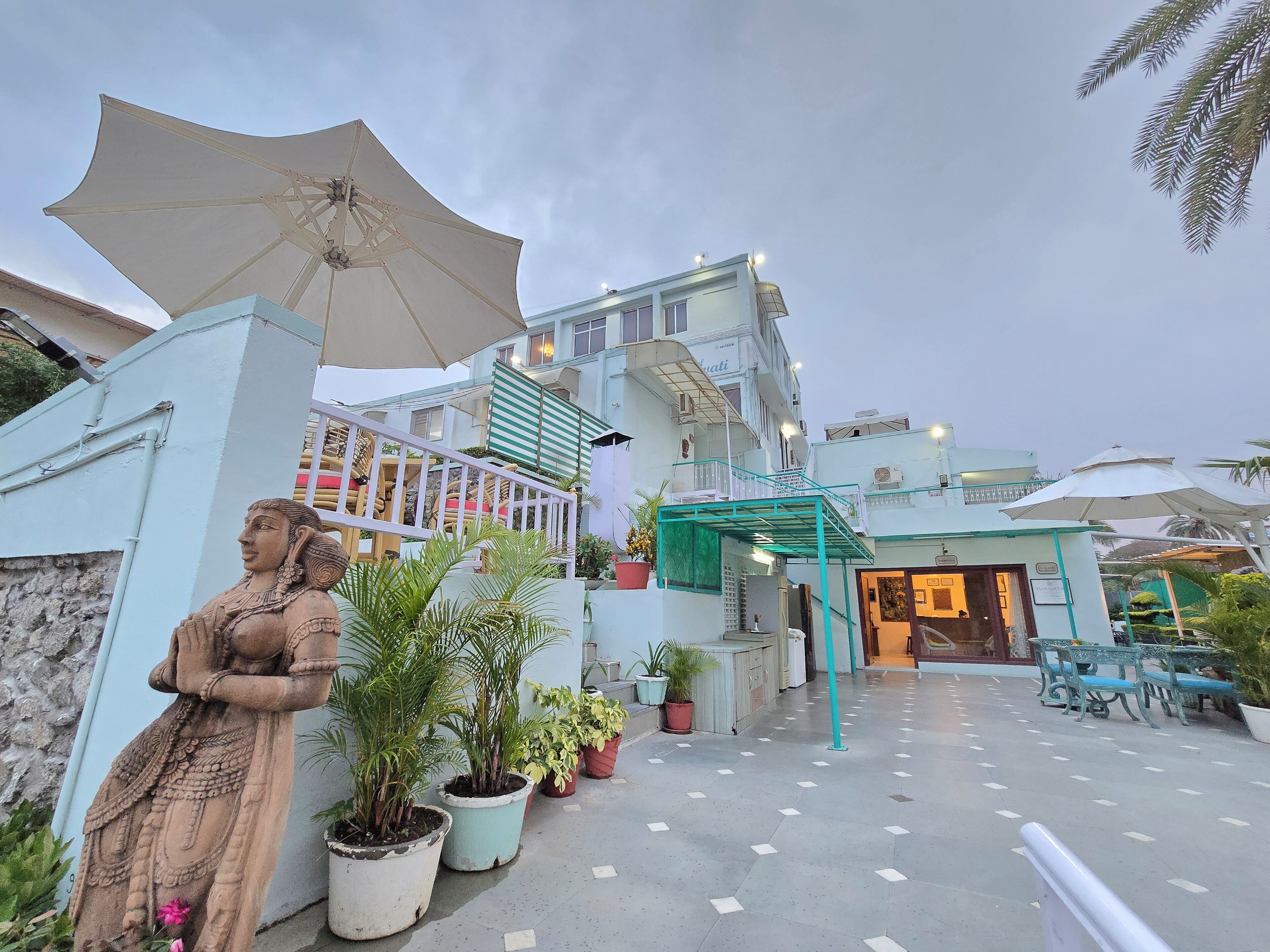 A hotel with a covered outdoor area, potted plants, and a statue.