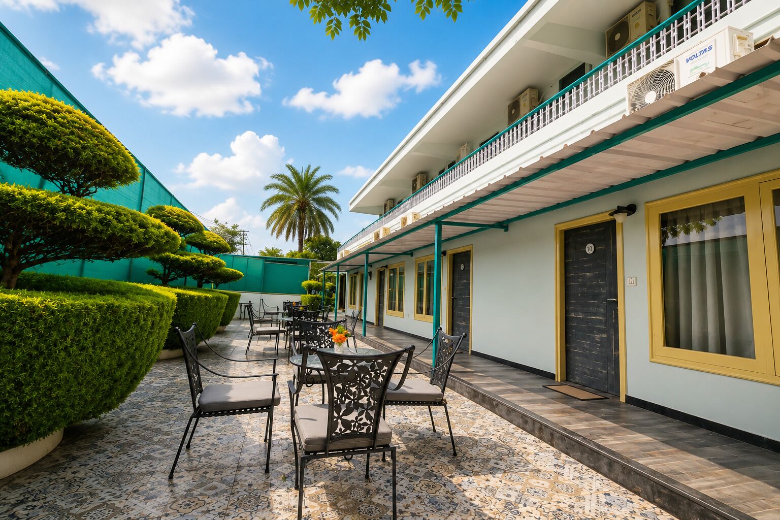 A courtyard with a seating area, a palm tree, and a building with a balcony.