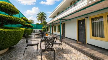A courtyard with a seating area, a palm tree, and a building with a balcony.