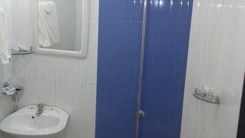 A bathroom with a sink, a mirror, a shower, and two buckets.