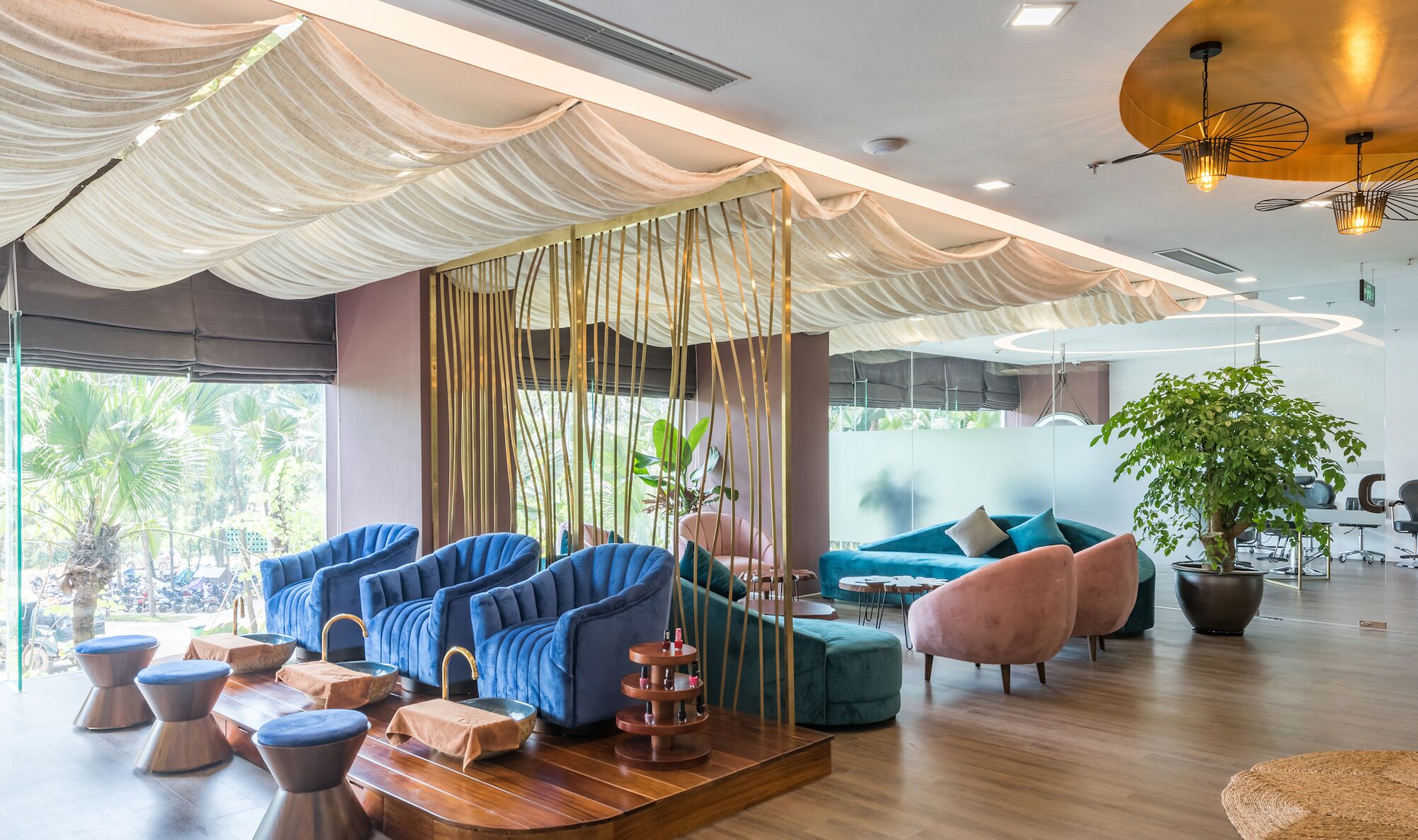 A modern lounge area with blue and teal sofas, a wooden coffee table, and a large potted plant.