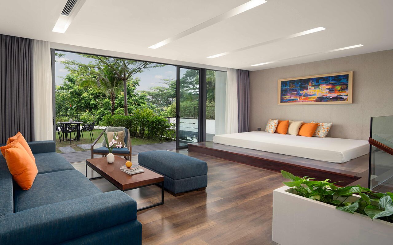 A modern living room with a sofa, a coffee table, and a view of greenery outside.