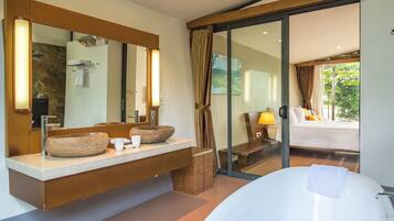 Une salle de bain moderne avec une grande baignoire, un lavabo en pierre et un grand miroir.