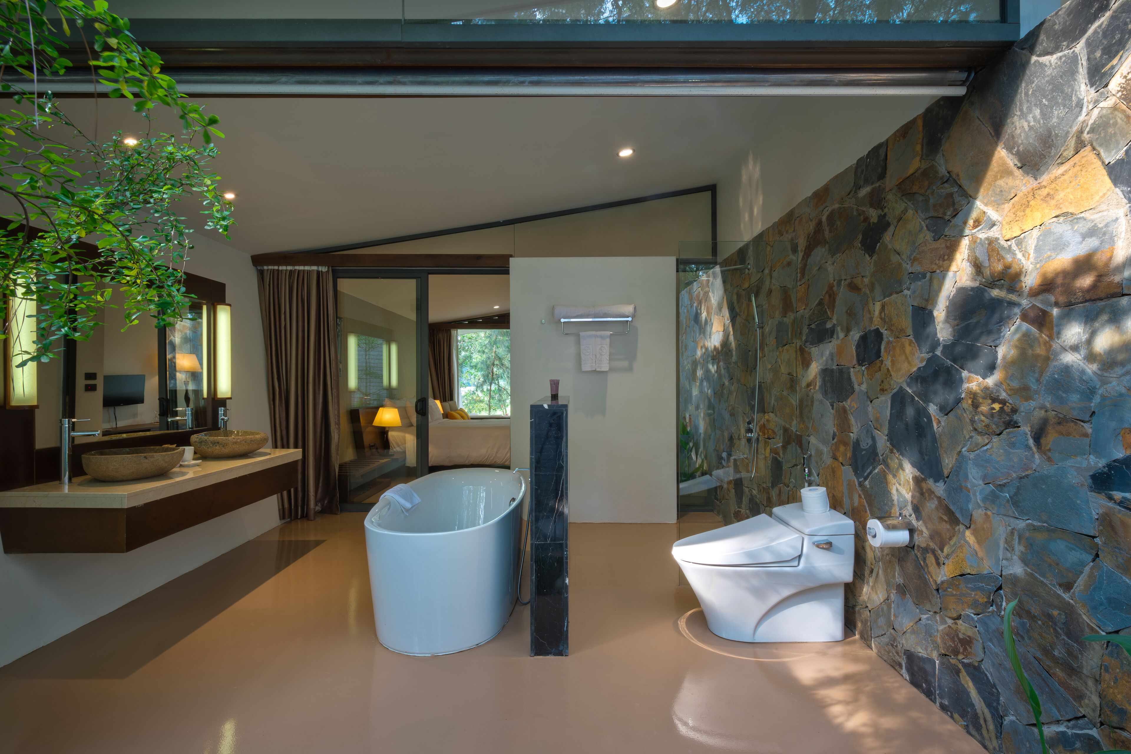 Un bagno moderno con una parete in pietra, una vasca da bagno ampia e un water.