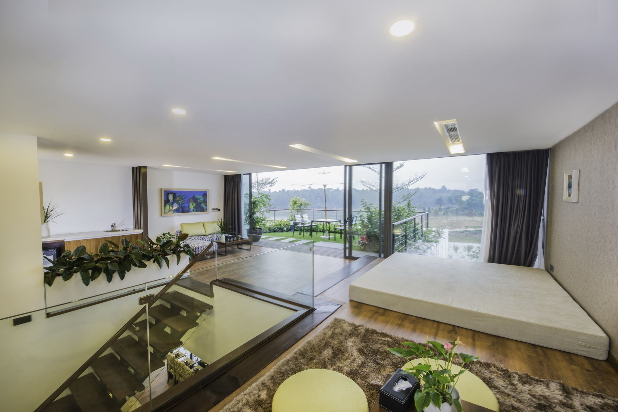 A modern living room with a staircase, a sofa, a coffee table, and a view of the outdoors.