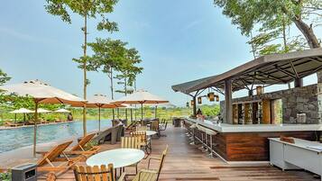 Relax by the pool surrounded by lush greenery and a wooden deck.
