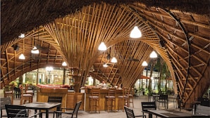 An indoor dining area with bamboo ceiling structures, wooden tables, and chairs. - Flamingo Dai Lai Resort - Managed by Flamingo Hotels & Resorts (Xuan Hoa)