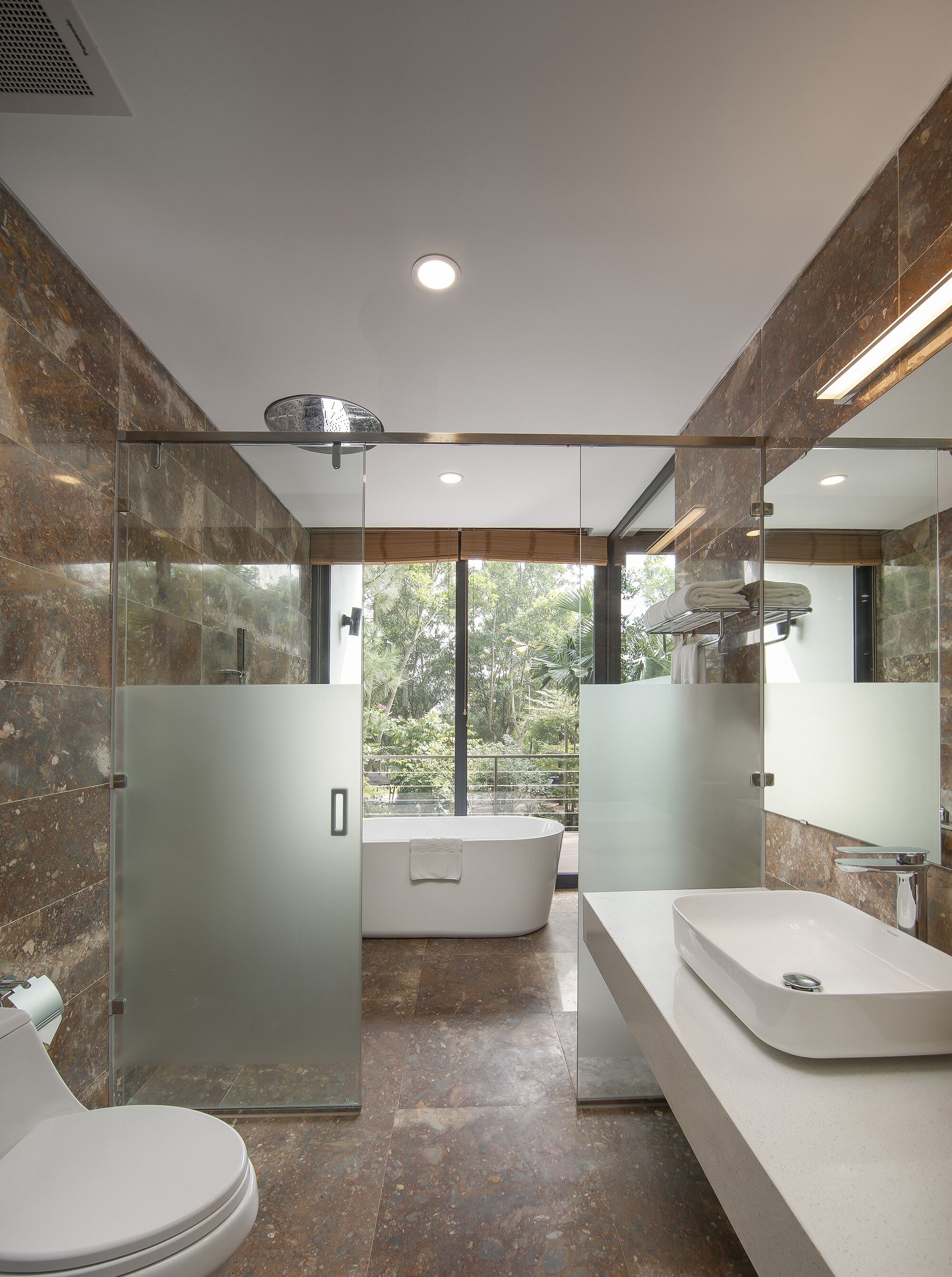 Un baño moderno con una bañera independiente, un espejo grande y una zona de ducha con cerramiento de vidrio.