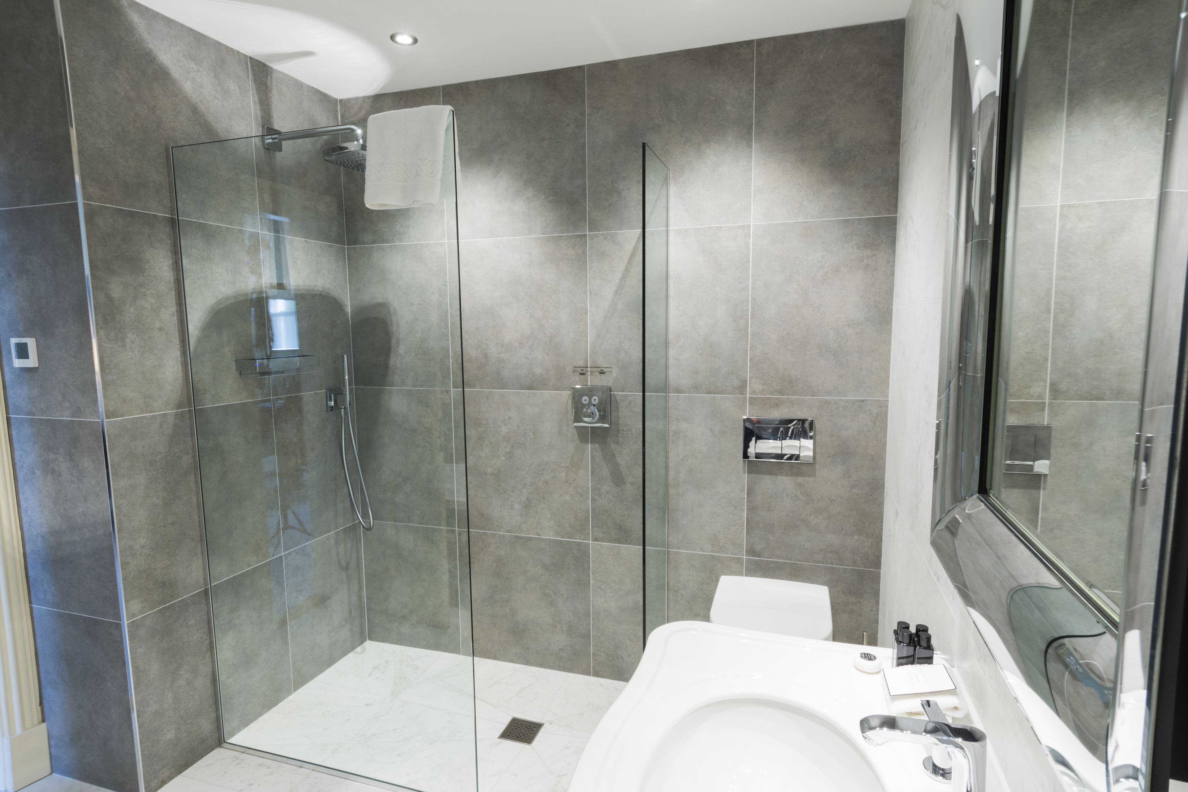 A modern bathroom with a glass-enclosed shower, a white sink, and a large mirror.