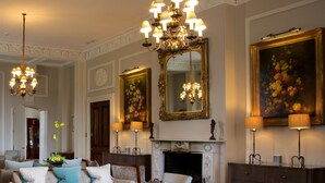 A spacious living room with a fireplace, elegant furniture, and a chandelier. - Storrs Hall Hotel (Windermere)