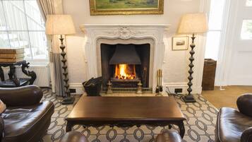 A living room with a fireplace, leather sofas, a wooden coffee table, and two floor lamps.