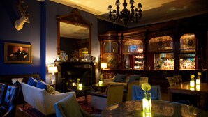 A room with a fireplace, seating area, and bar. - Storrs Hall Hotel (Windermere)