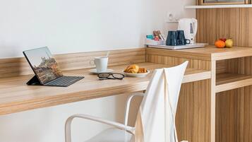 Una cocina moderna con encimera de madera, una computadora portátil, una cafetera y una silla blanca.