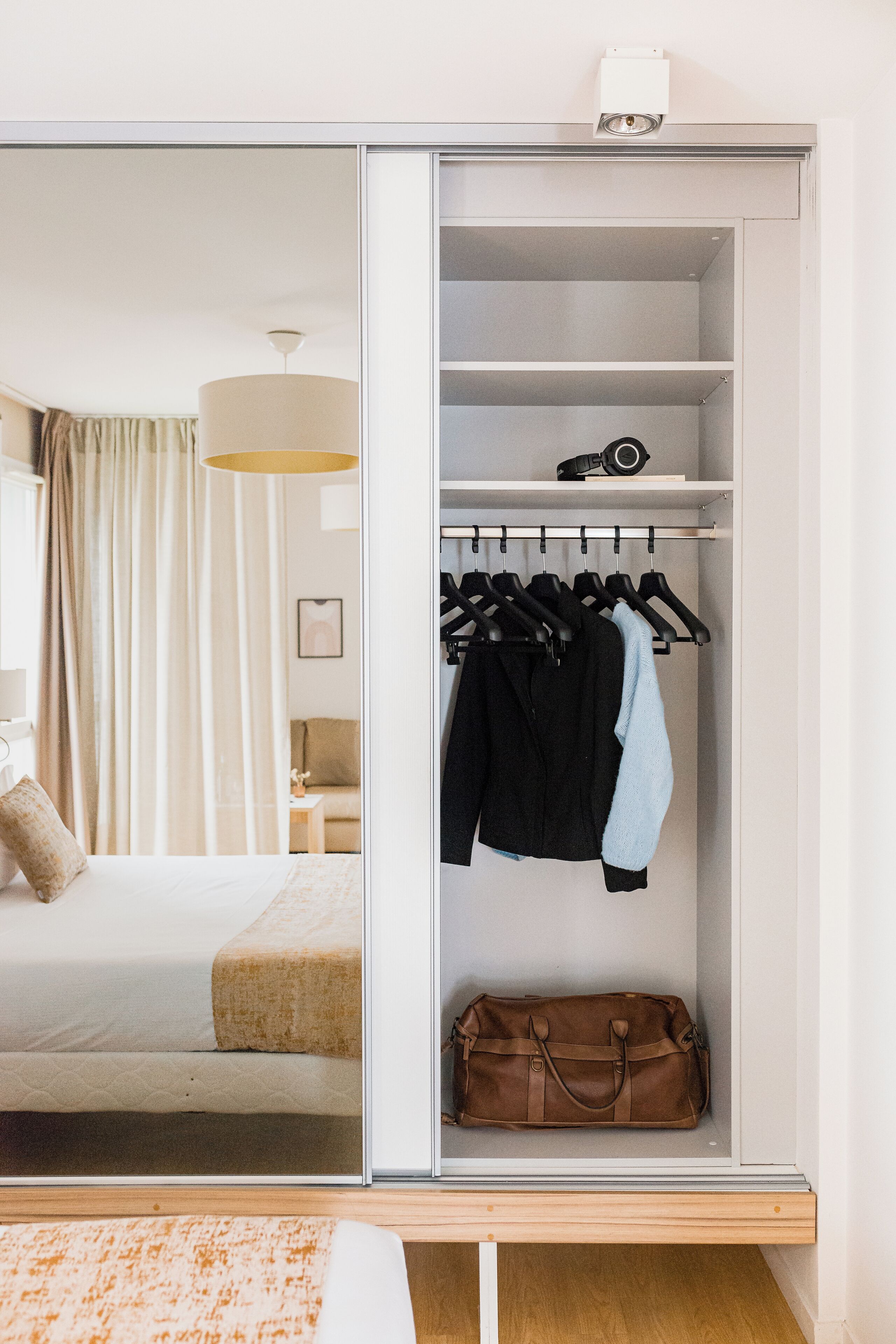 Ein Schlafzimmer mit Bett, Nachttisch, Kleiderschrank und einer Pendelleuchte.