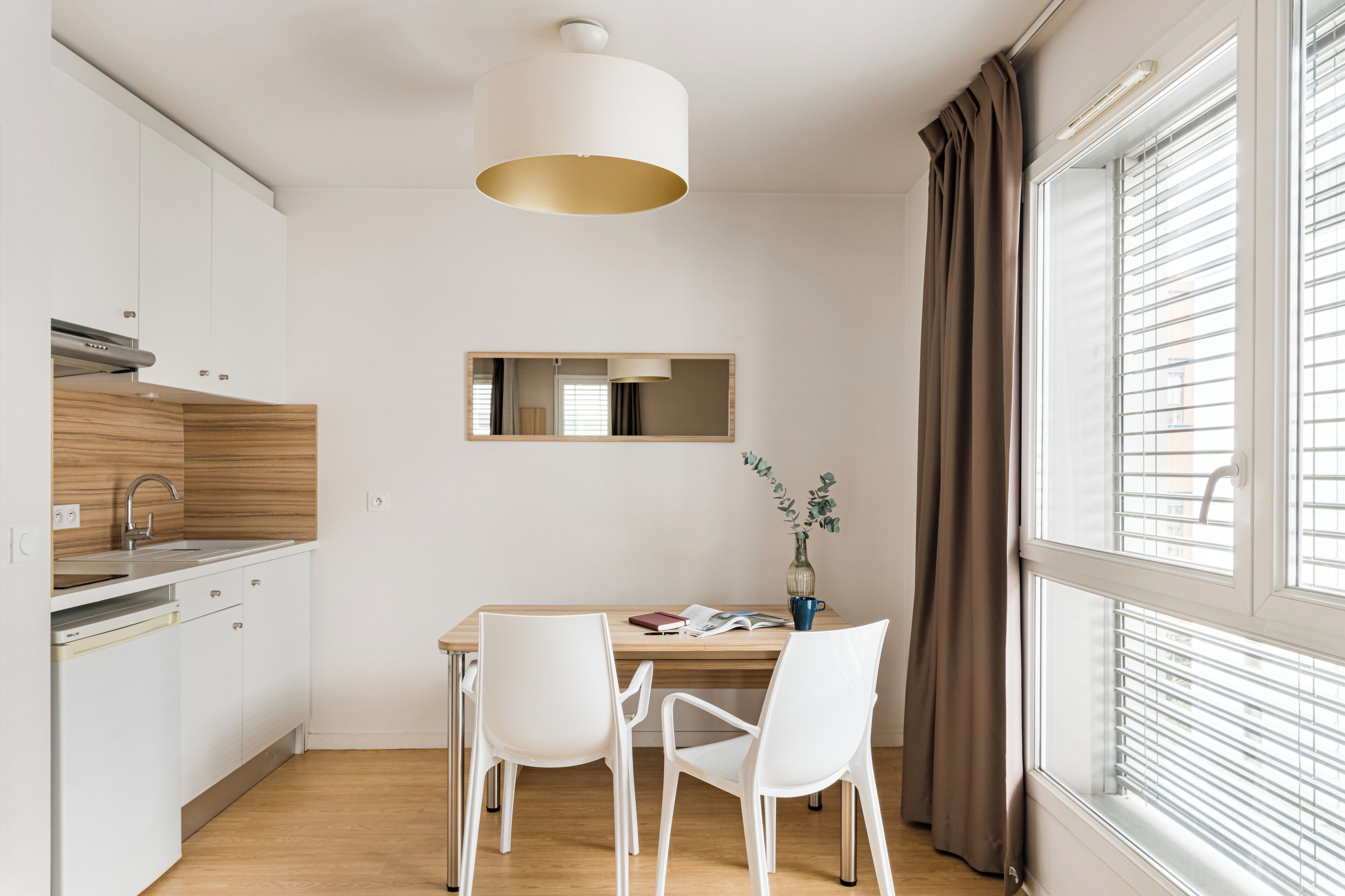 Una cocina moderna con armarios blancos, encimera de madera y una lámpara colgante.