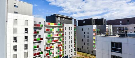 Un moderno edificio de apartamentos con varios balcones, ventanas amplias y un patio.