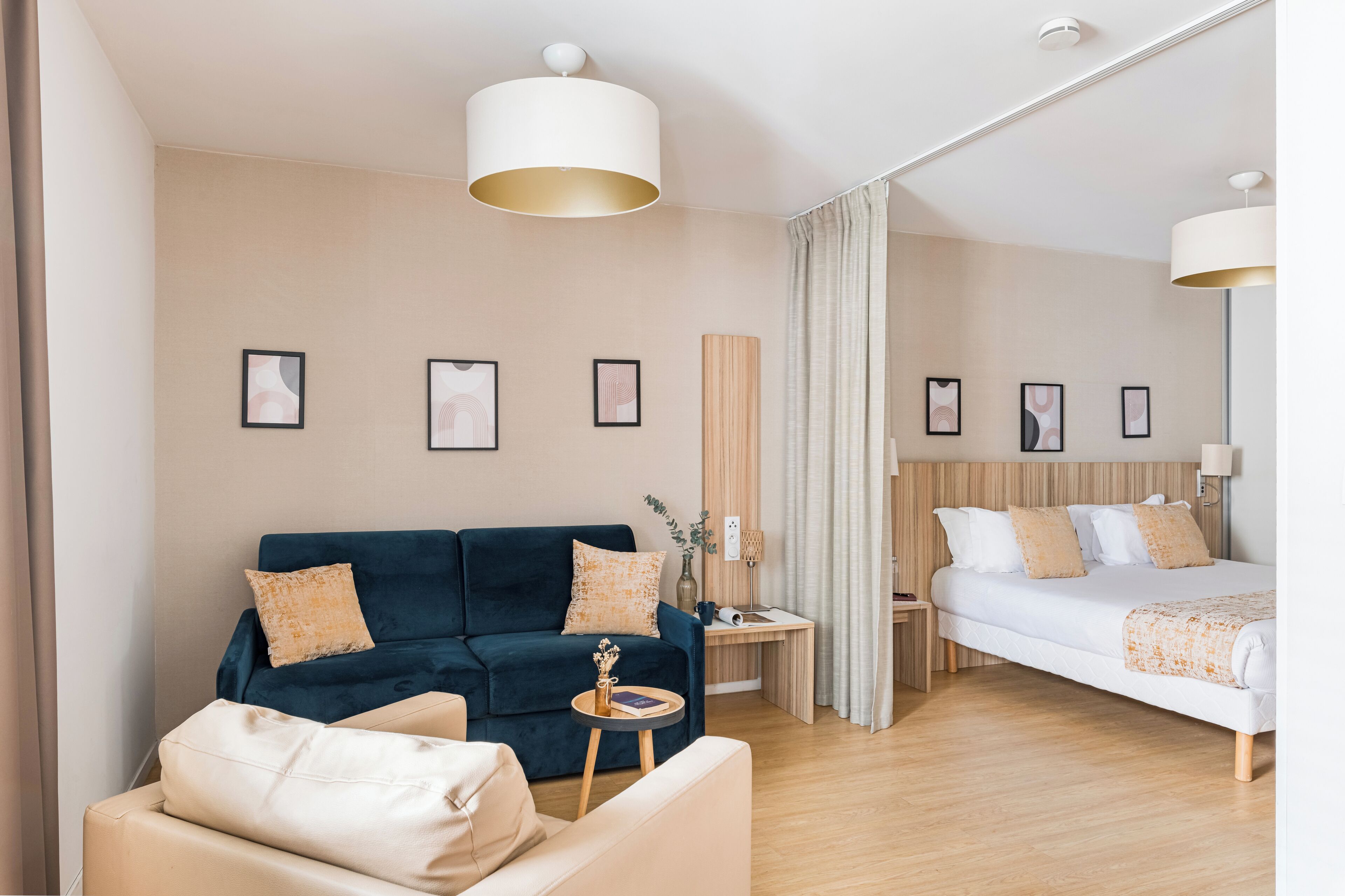 Een moderne hotelkamer met een donkerblauwe bank, een wit bed en een houten vloer.