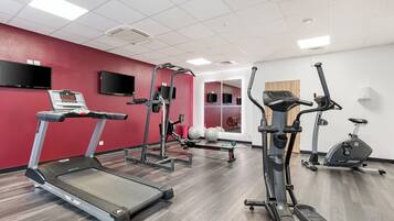 Une salle de sport équipée de tapis de course, de vélos elliptiques et de vélos d’appartement.